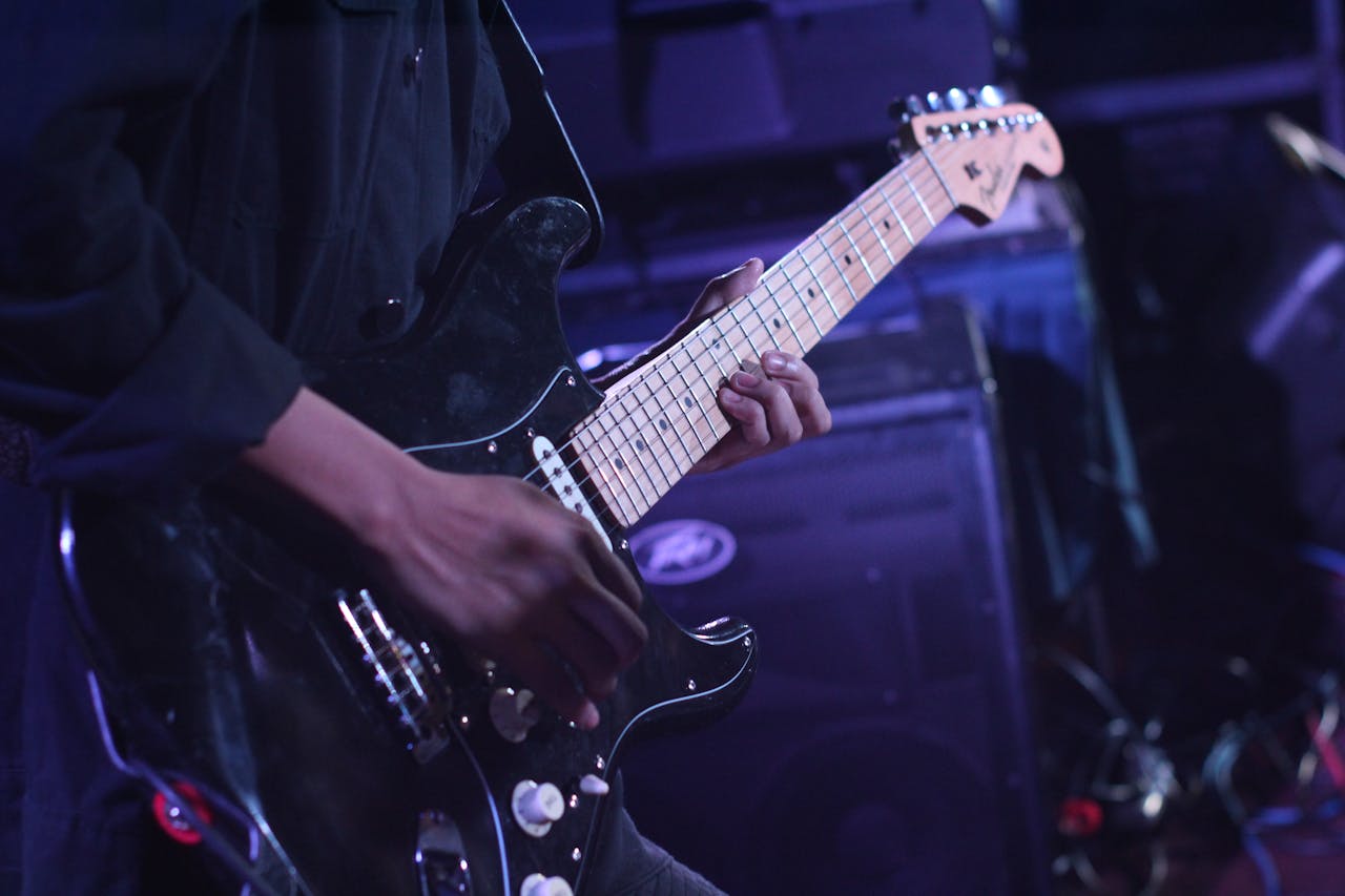 why-choose-us-02 Musician playing an electric guitar on stage during a live performance.